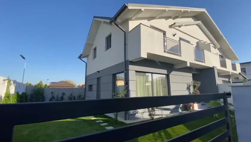 Casă cu acoperiș înclinat, balcon și gazon în fața terasei